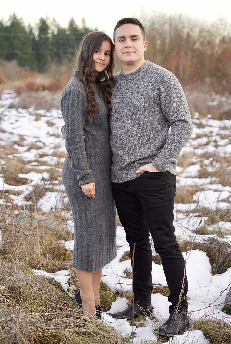 A young couple standing in a snowy field
